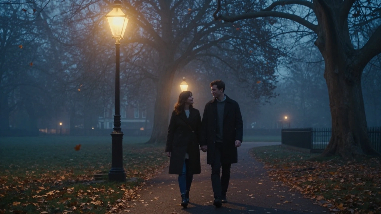 A couple walks hand in hand through a misty London park at dusk, leaves drifting around them.